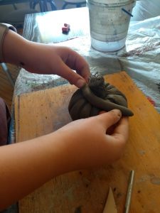 Uczeń rzeźbi dynię z gliny