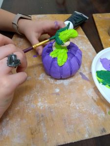 Uczeń maluje glinianą ceramiczną  dynię