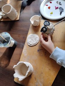 Uczeń maluje glinianą ceramiczną  sowę