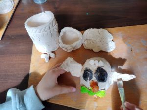 Uczeń maluje glinianą ceramiczną  sowę