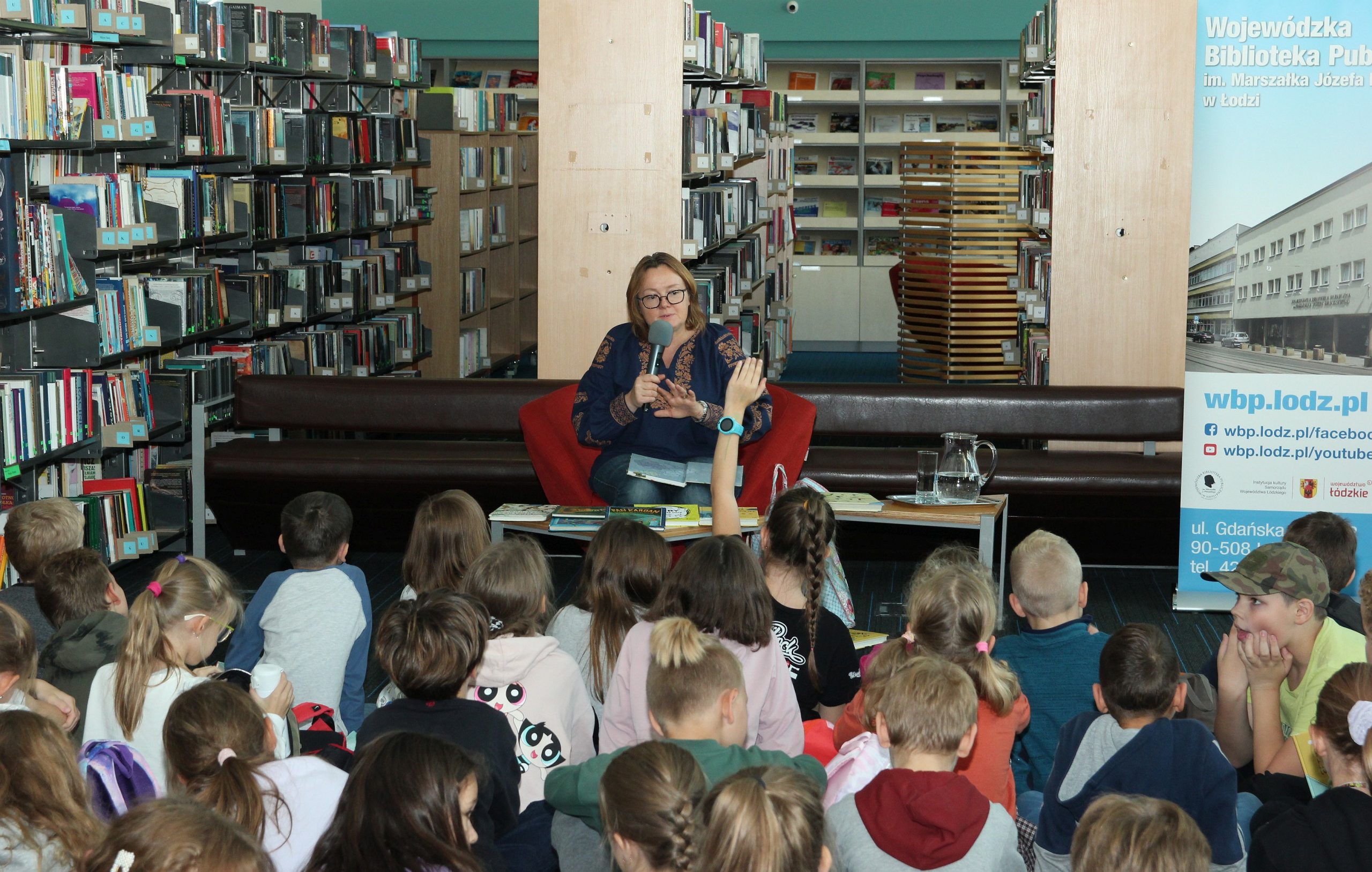 Autorka książek dla dzieci -  Justyna Bednarek w otoczeniu uczestników spotkania autorskiego.