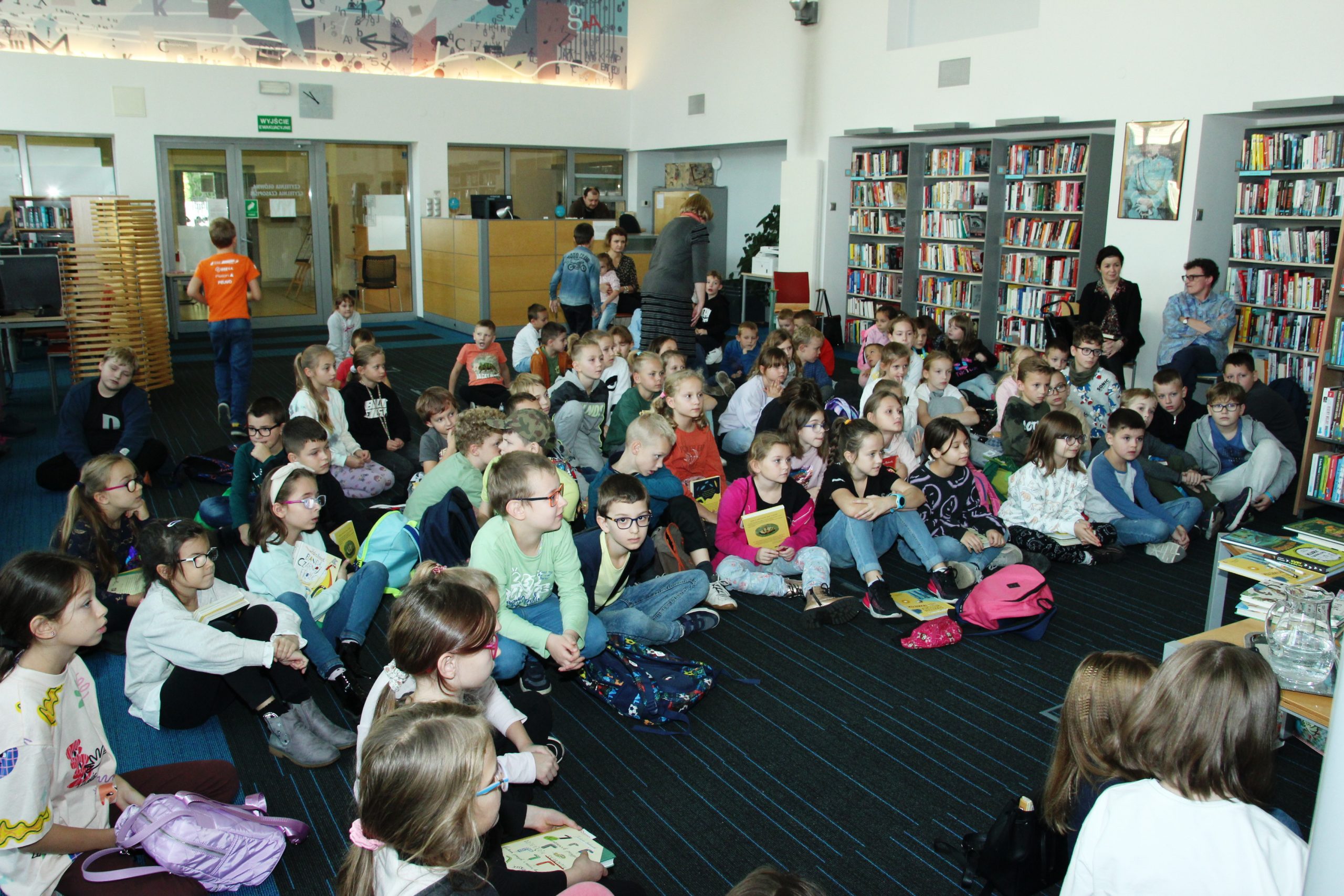 Grupa dzieci uczestniczących w spotkaniu autorskim z Justyną Bednarek w otoczeniu 