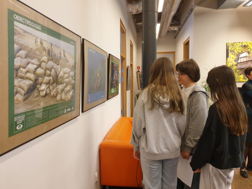 Uczniowie oglądają wystawę plakatów francuskiego fotografa Yanna Arthusa-Bertranda